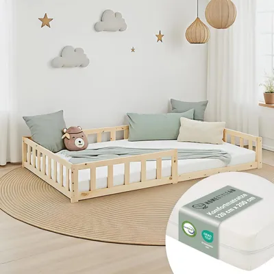 A child's bed with a wooden frame and guardrails, set up in a bedroom with decorative clouds and stars on the wall.