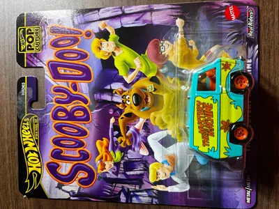 A Hot Wheels 'Scooby-Doo!' The Mystery Machine toy car in its packaging, with cartoon characters from the show depicted on the packaging.