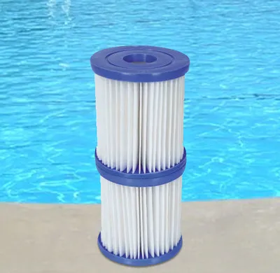 Two stacked pool filter cartridges with blue caps sit on a tan surface in front of a blue pool.