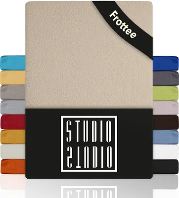 A product image showing a beige fitted sheet with a black band at the top displaying the text 'Frottee'. To the left and right of the main sheet are stacks of smaller sheets in various colors, showcasing the available color options. Below the main sheet is