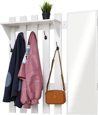 A white coat rack with a shelf, hooks, and a mirror, holding two jackets and a handbag.