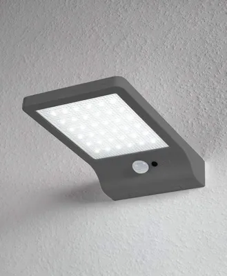 A solar-powered LED light fixture mounted on a textured wall.