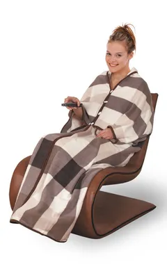 A woman sitting in a chair, wrapped in a blanket and holding a remote control.