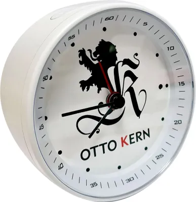 A close-up side view of a white analog alarm clock with a black lion logo and the brand name 'OTTO KERN' printed on its face.