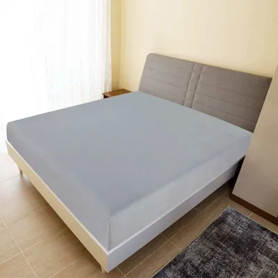 A bed with a gray fitted sheet in a bedroom.