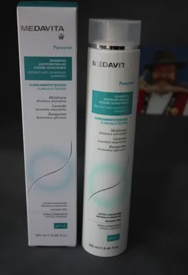 A box and bottle of Medavita Puroxine Instant Anti-Dandruff Shampoo are displayed side-by-side on a dark gray surface.