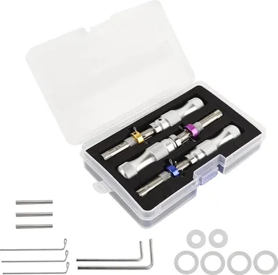 A set of lock picking tools in a clear plastic case, with additional small metal rods and rings laid out below.