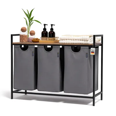 A laundry basket with three compartments and a shelf on top, decorated with bottles and plants.