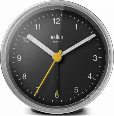 A close-up, front-facing view of a Braun alarm clock with a black face and silver casing.