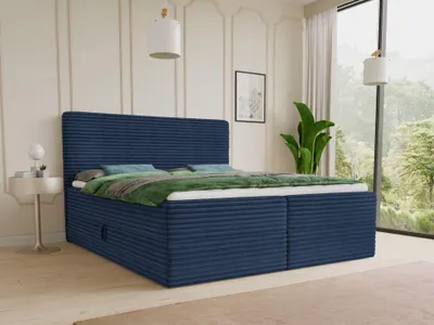 A blue corduroy boxspring bed with storage drawers is shown in a well-lit bedroom with a large window overlooking a forest.