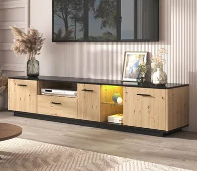 A modern living room with a TV stand, decor, and a rug.