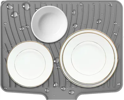 A gray silicone drying mat with water droplets, holding three white plates and a white bowl. The plates have a thin gold rim.