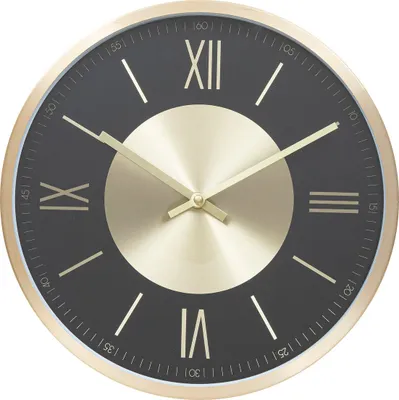A close-up view of a modern wall clock with a black face and gold accents.