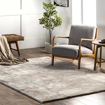 A cozy living room scene with a rug, armchair, and bench.