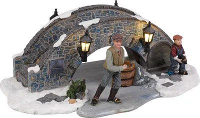 A miniature Christmas village scene featuring a stone bridge with two children ice skating.