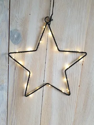 A star-shaped LED light decoration hanging against a wooden background.