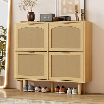 A wooden shoe cabinet with four doors and rattan fronts, with shoes neatly arranged underneath. A mirror is partially visible on the left.