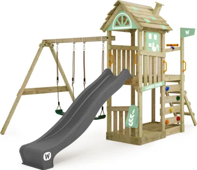 A wooden playground set with a slide, swings, and climbing wall, set against a white background.