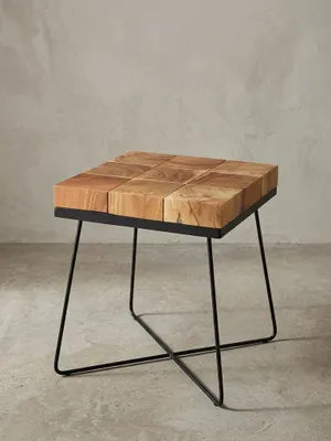 Quadratischer Anstelltisch in Frontalansicht mit einer markanten Massivholzplatte aus brauner Akazie und einem filigranen, mattschwarzen Metallkreuzgestell im Retro-Design._#sku_SAFWL5.301#