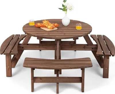 A wooden picnic table set with benches and a vase of flowers on the table.