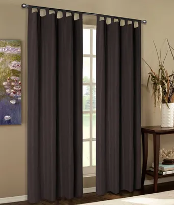 A pair of dark brown tab-top curtains hangs in front of a window, with a painting on the left and a side table with decorative items on the right.