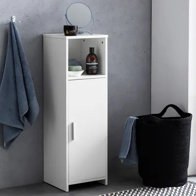 A bathroom scene with a white cabinet, towels, and a laundry basket.