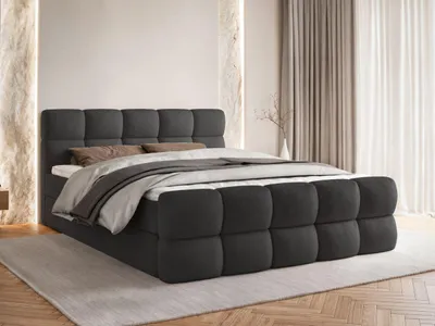 A dark gray upholstered bed with a tufted headboard and footboard, set in a bedroom with neutral-toned walls and curtains.