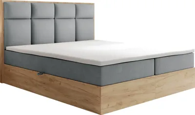 A studio shot of a boxspring bed with a headboard, mattress, and topper.
