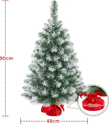 A small, artificial Christmas tree with snow-like flocking, standing on a red fabric base. Dimensions are indicated by measurement lines.