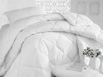A white duvet is neatly arranged on a bed, with a pillow and a book visible.