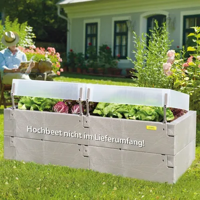 A raised garden bed with plants and a person sitting in the background.