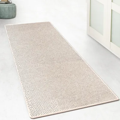A cream-colored rug with a textured pattern is laid out on a light gray floor, next to a white cabinet.