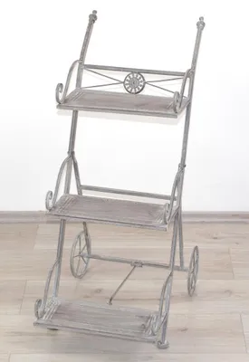 A gray metal plant stand with three shelves and wheels.
