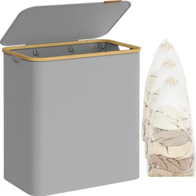 A grey laundry basket with a bamboo rim and lid, shown with three laundry bags filled with clothes.
