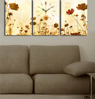 A triptych wall clock with a floral design, featuring a clock face on the center panel, displayed above a sofa.