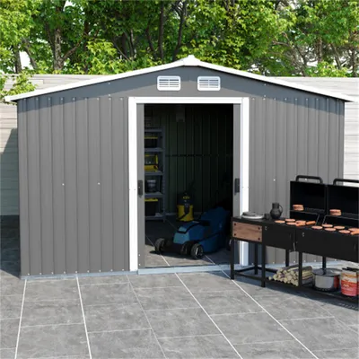 A gray metal shed with an open door, placed on a tiled patio with two grills in front of it.