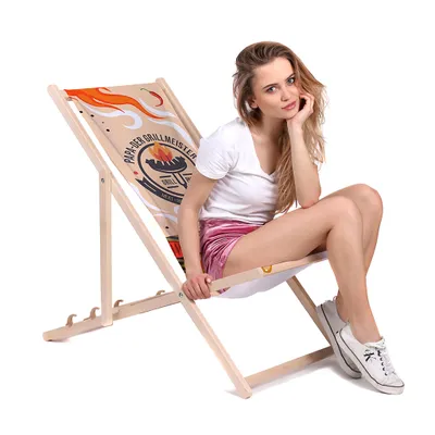 A woman is sitting on a foldable wooden deck chair with a grill-themed design.