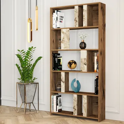 A tall, narrow bookshelf with a walnut finish and white marble accents, filled with books and decorative items, stands against a white paneled wall.