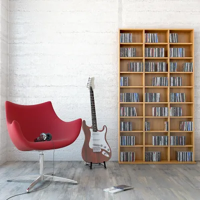 A red chair, an electric guitar, and a bookshelf filled with CDs in a room.