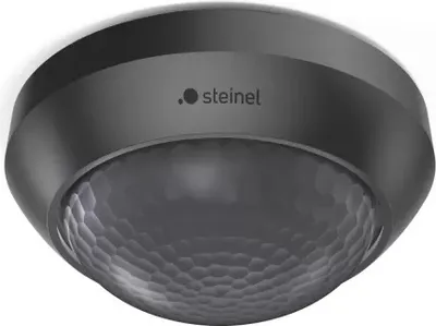 A black and gray motion sensor mounted on a white ceiling.