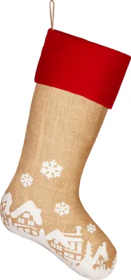 A Christmas stocking with a red cuff and a burlap body decorated with a winter village scene and snowflakes.