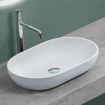 A white oval-shaped sink with a chrome faucet is placed on a gray countertop against a green wall.