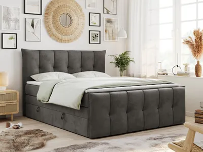 A bedroom scene featuring a large bed with a dark gray upholstered headboard and base, dressed with white bedding. The room has a window with sheer curtains, decorative wall art, and a small plant.