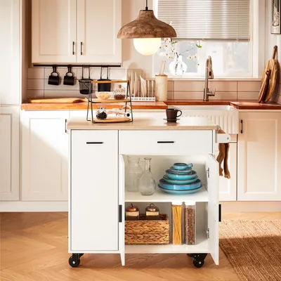 A kitchen scene with a white kitchen island cart, cabinets, and a sink.