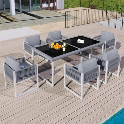 An outdoor patio set with a table and chairs, set on a wooden deck next to a pool.