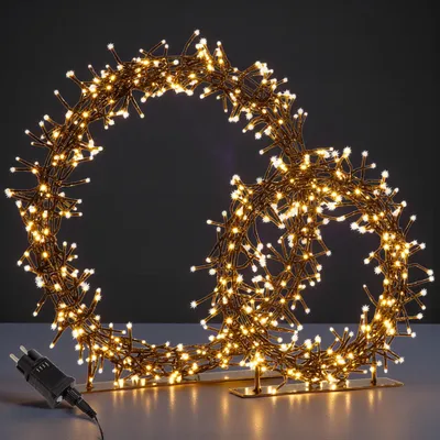 A decorative LED light ring shaped like a stylized number '8' or infinity symbol, illuminated with warm white lights, placed on a surface with a dark background.