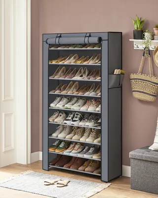A fabric shoe rack filled with shoes, placed near a wall and a doorway.