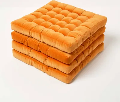 A stack of four orange seat cushions on a white background.