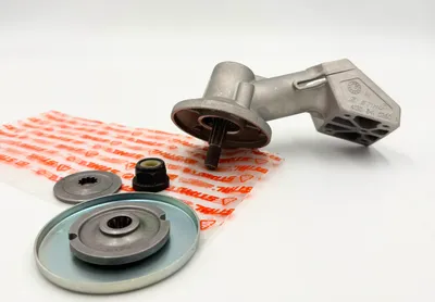 A collection of STIHL parts for a trimmer, including a gearbox and mounting hardware, laid out on a white surface.