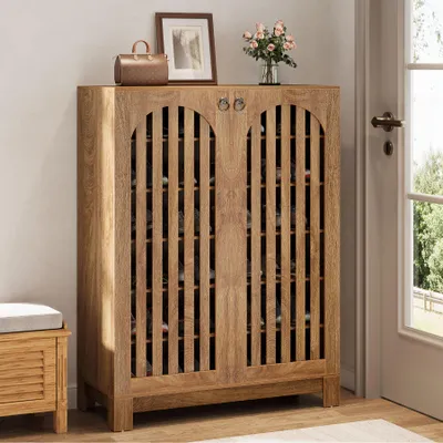 A wooden shoe cabinet with slatted doors is shown in a hallway next to a door and a bench.